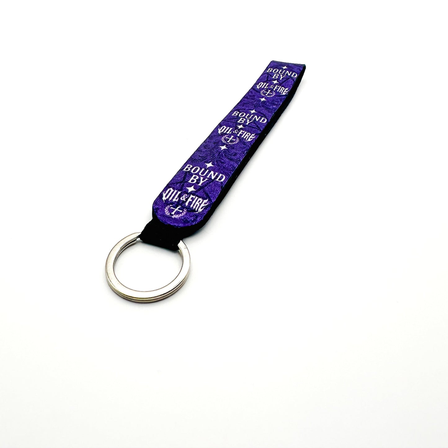 a keychain that is purple black and white that says bound by Oil and fire that has a pentagram