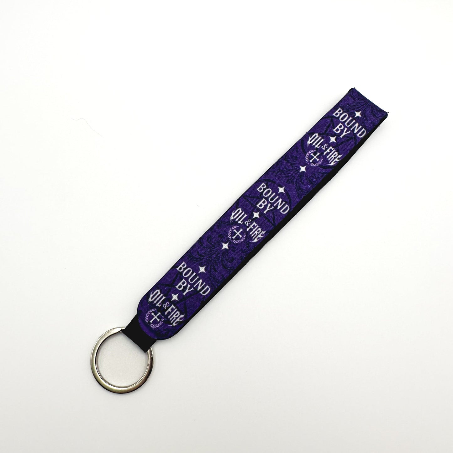 a keychain that is purple black and white that says bound by Oil and fire