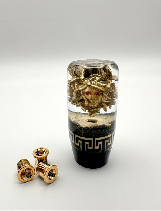A golden Medusa Shift Knob with red eyes and gold dust for manual automatic cars for shifting gears with your shifter