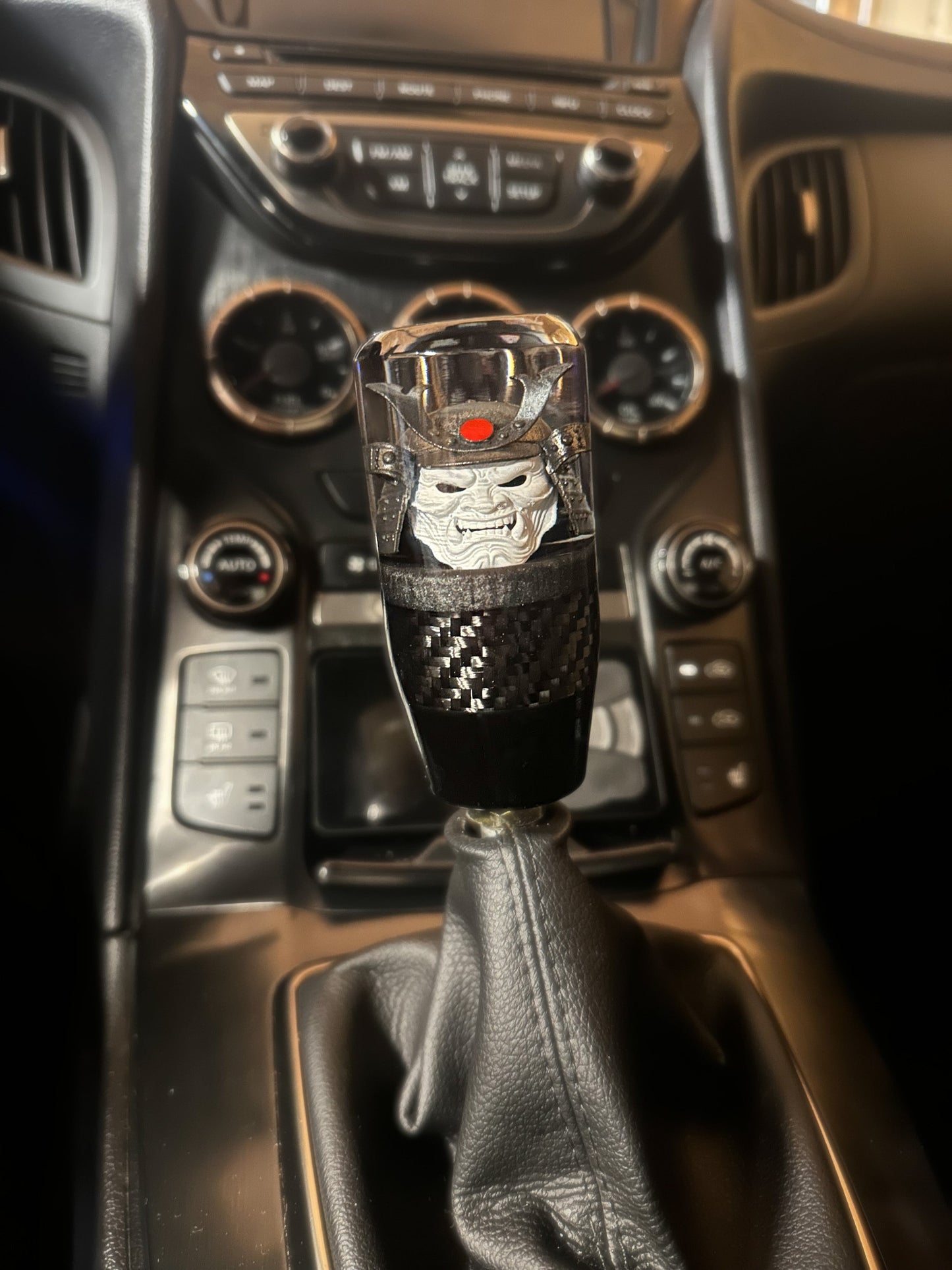 oni samurai shift knob installed in Genesis coupe ultimate.  white face, gunmetal helmet, red accent. features real carbon fiber and black base. 