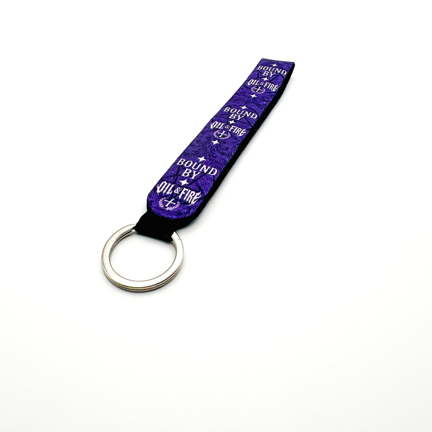 a keychain that is purple black and white that says bound by Oil and fire that has a pentagram