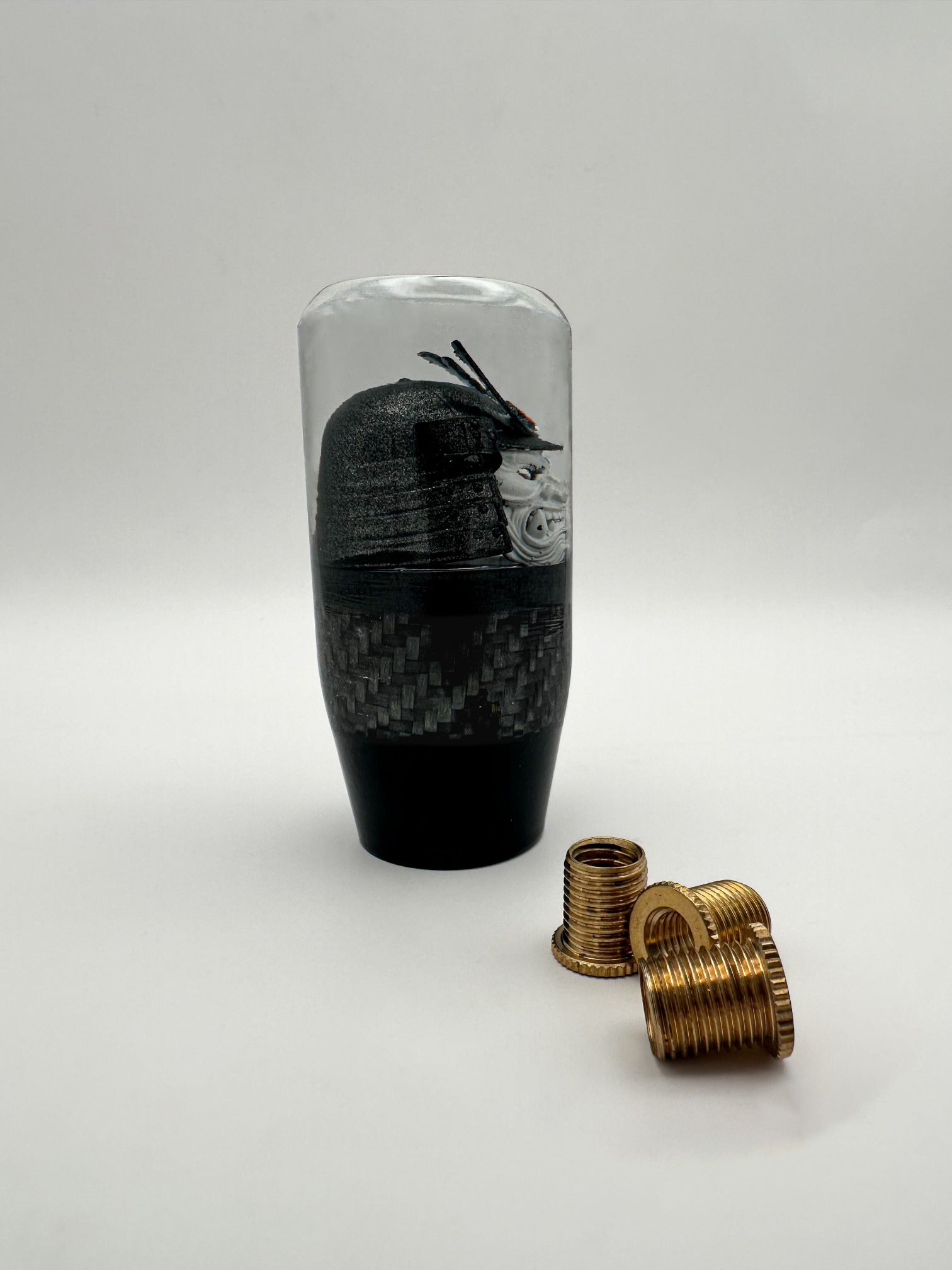 side view oni samurai shift knob, white face, gunmetal helmet, red accent. features real carbon fiber and black base. 