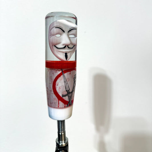 Guy Fawkes mask shift knob made by nice knob, bro. an American shift knob company. Shifter transitions from Fawkes mask to red layer, followed by v for vendetta inspired design. dead rose crossed with dagger on bloody circle. in background a legion of anonymous. final layer white. great universal stick shifter weighted for cars. 